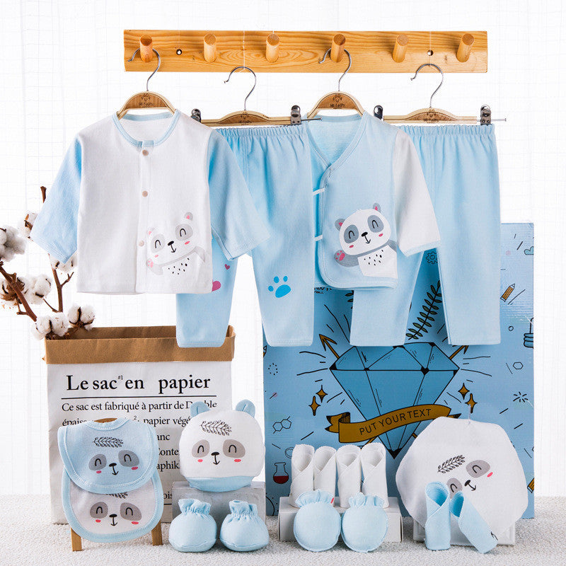 Newborn gift box with blue and white baby clothes including tops, pants, bibs, booties, and hats with animal prints