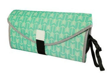 Folded portable baby changing pad with green arrow pattern and black strap for easy carrying