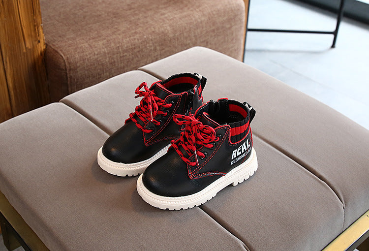 Black and red boys and girls warm martin boots with white soles and red laces on gray cushion