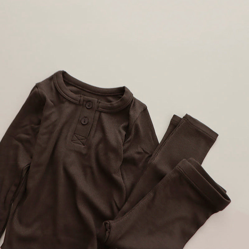 Dark brown soft cotton pajamas for toddlers with long sleeves and buttoned neckline set on a light background