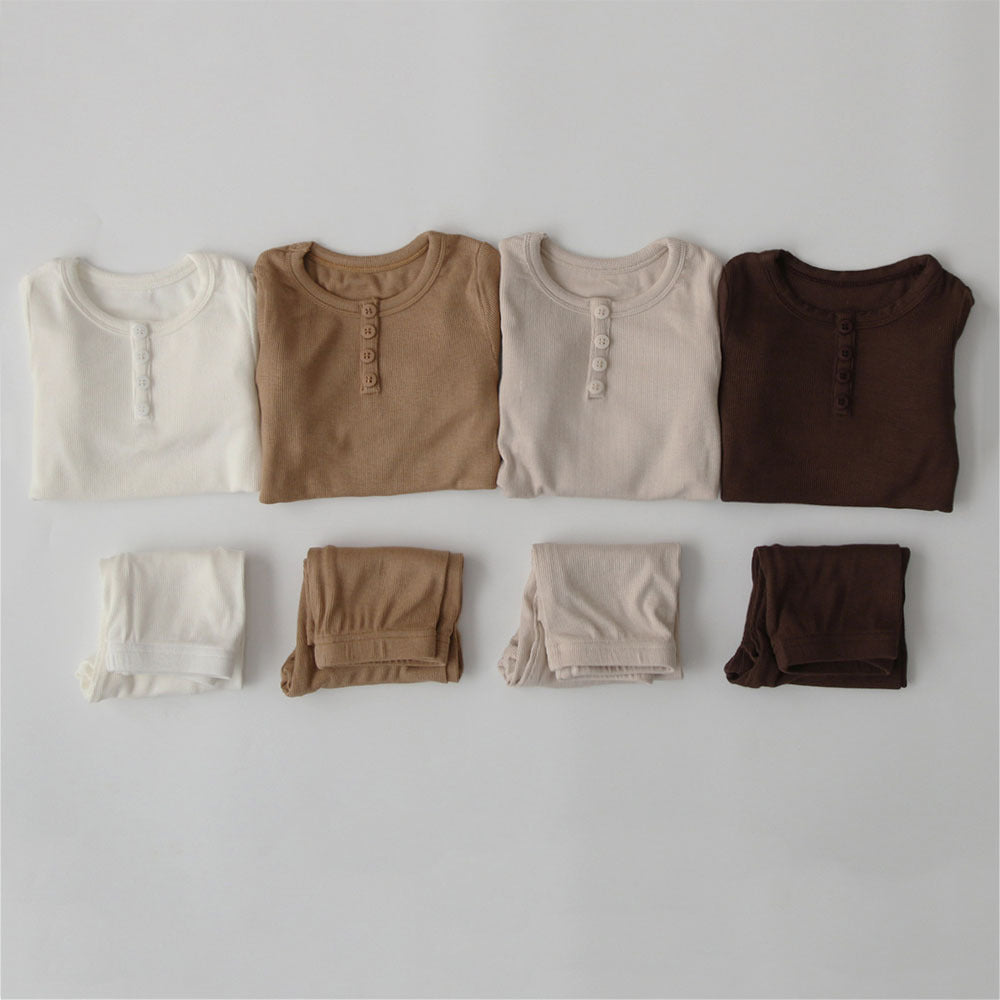 Set of soft cotton pajamas for toddlers in white, beige, brown, and dark brown colors neatly folded