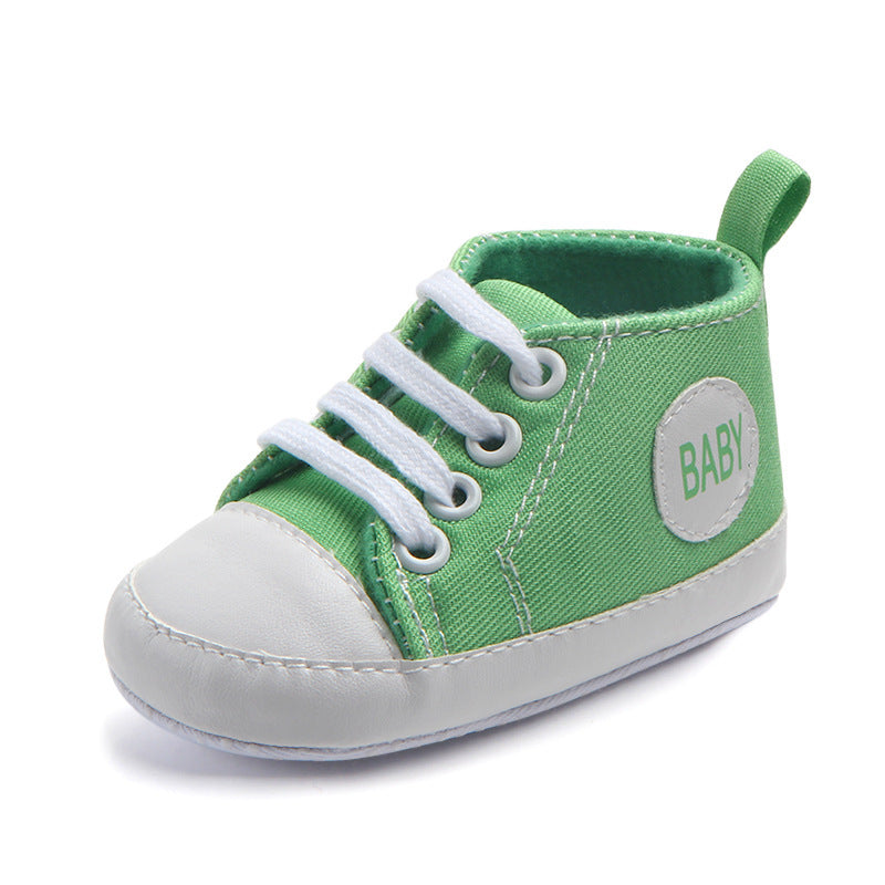 Green soft sole baby sneakers with white laces and toe cap featuring baby patch