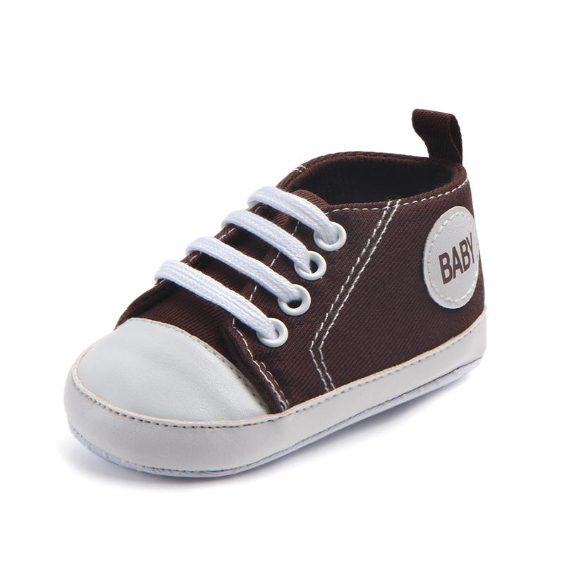 Brown and white soft sole baby sneakers with white laces and baby label on the side