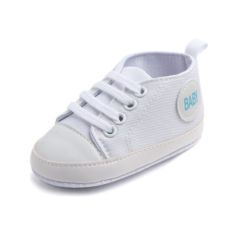 White soft sole baby sneakers with lace-up design and baby label on side for infants