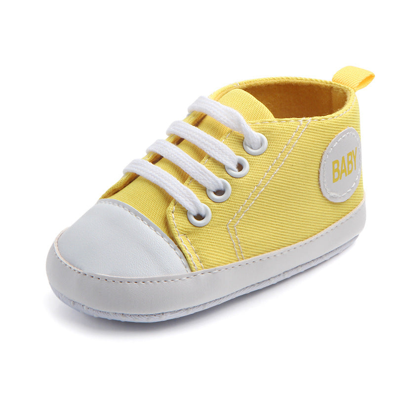 Yellow soft sole baby sneakers with white laces and toe cap for infants