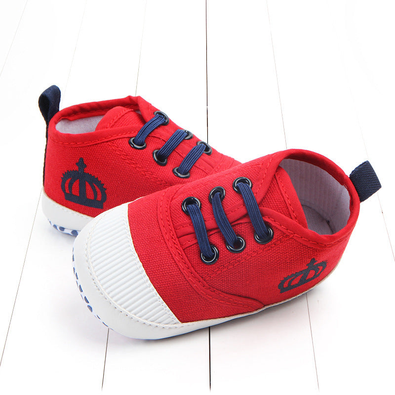 Red toddler canvas sneakers with navy blue laces and crown design on white sole for kids