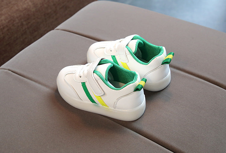 White toddler velcro light up sneakers with green and yellow accents on gray surface