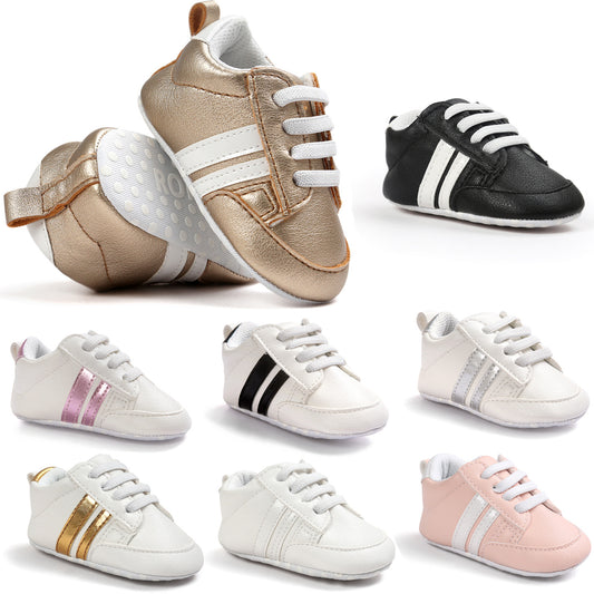 Collection of infant moccasin shoes in various colors including gold, black, white, pink, and metallic stripes